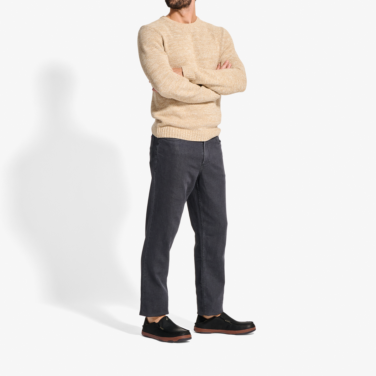Man wearing toffee-colored knit crewneck sweater and black denim jeans with black and burgundy shoes.