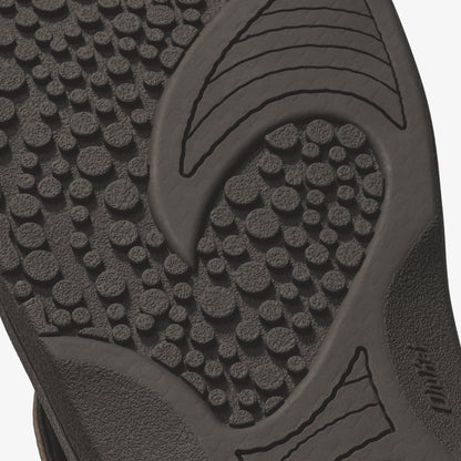 Dark textured sole of slide sandal with raised circular tread pattern and curved grip lines.