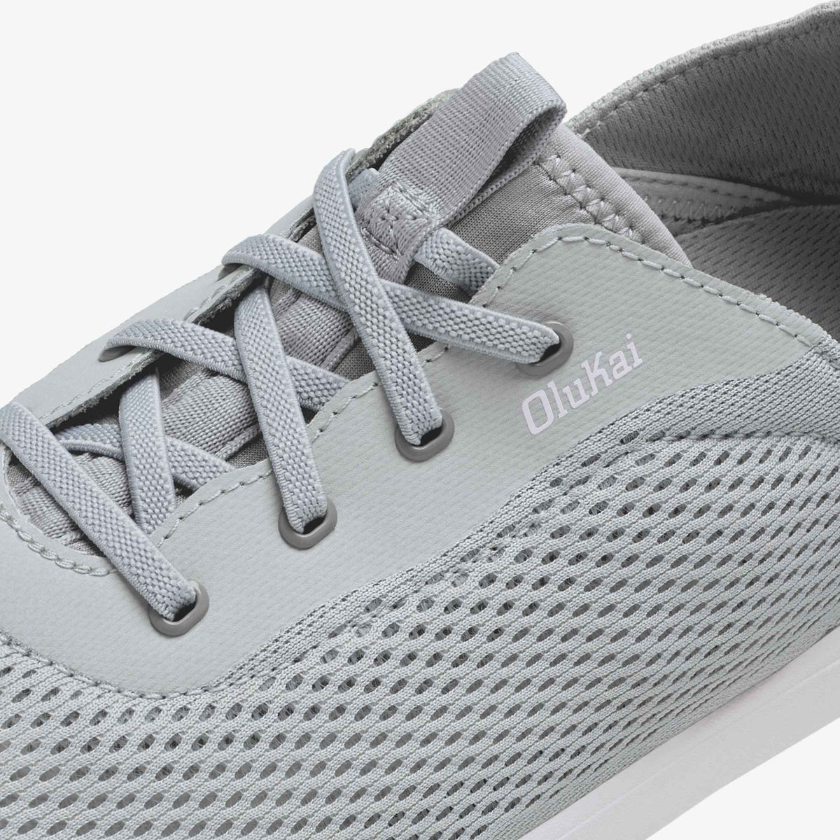 Grey lace-up athletic shoe with mesh and synthetic upper, showing Olukai branding on the side.