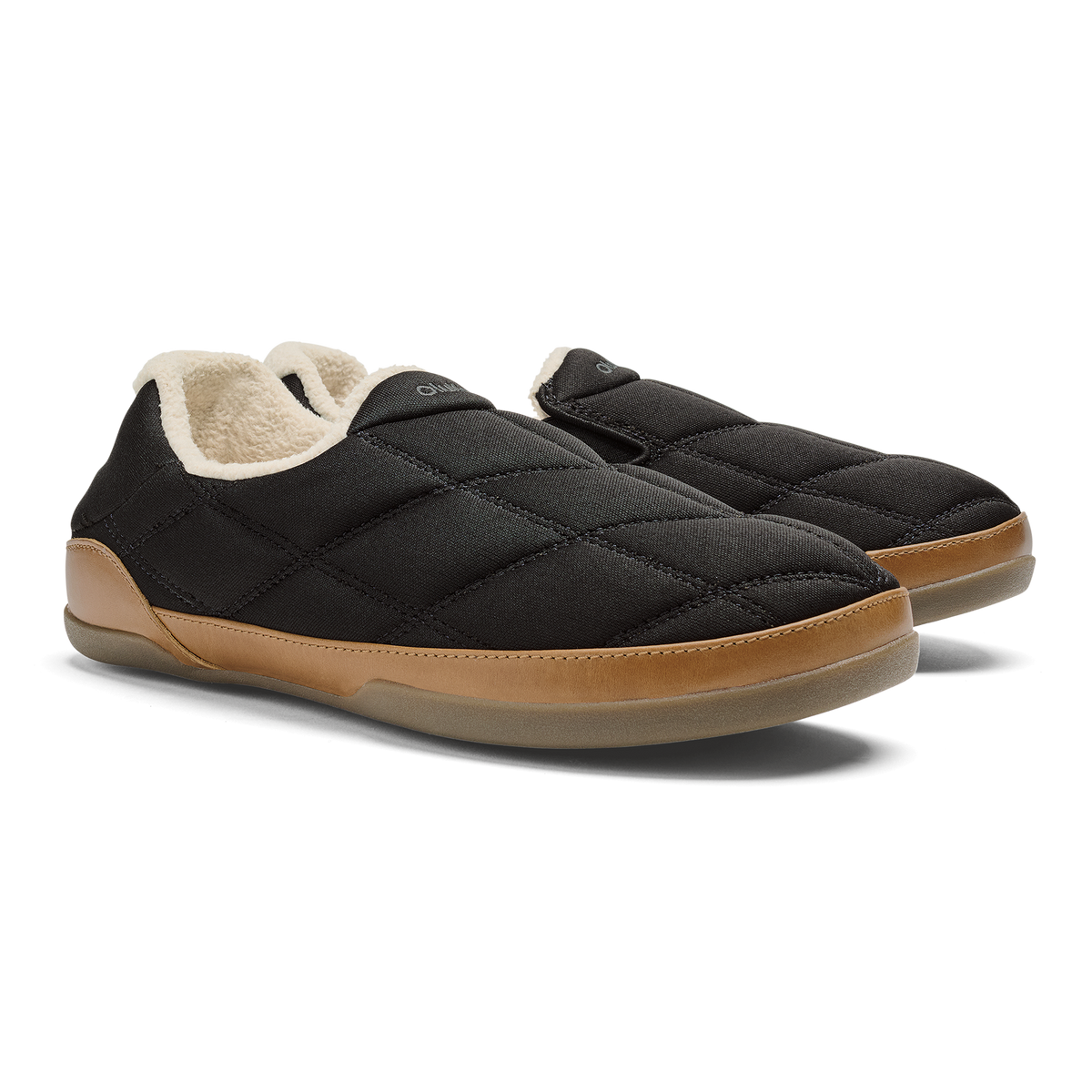Black quilted slip-on slippers with tan sole and cream fleece lining, shown from the side.
