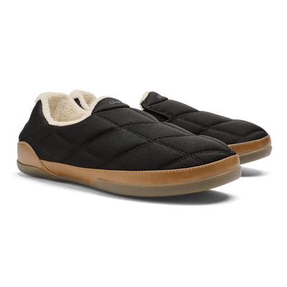 Black quilted slip-on slippers with tan sole and cream fleece lining, shown from the side.