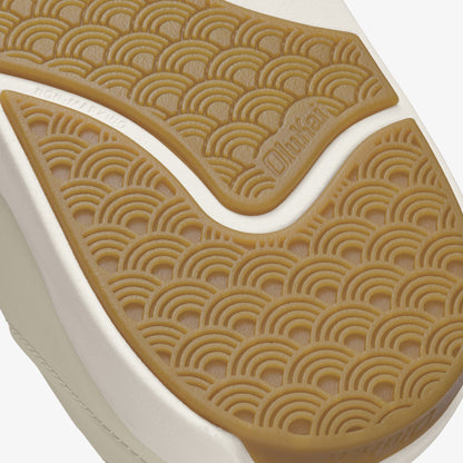 Tan and white shoe sole with repeating semicircle embossed pattern and brand text visible on upper section.