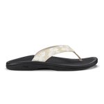 Black flip-flop sandal with beige thong strap featuring white floral pattern and dotted design.