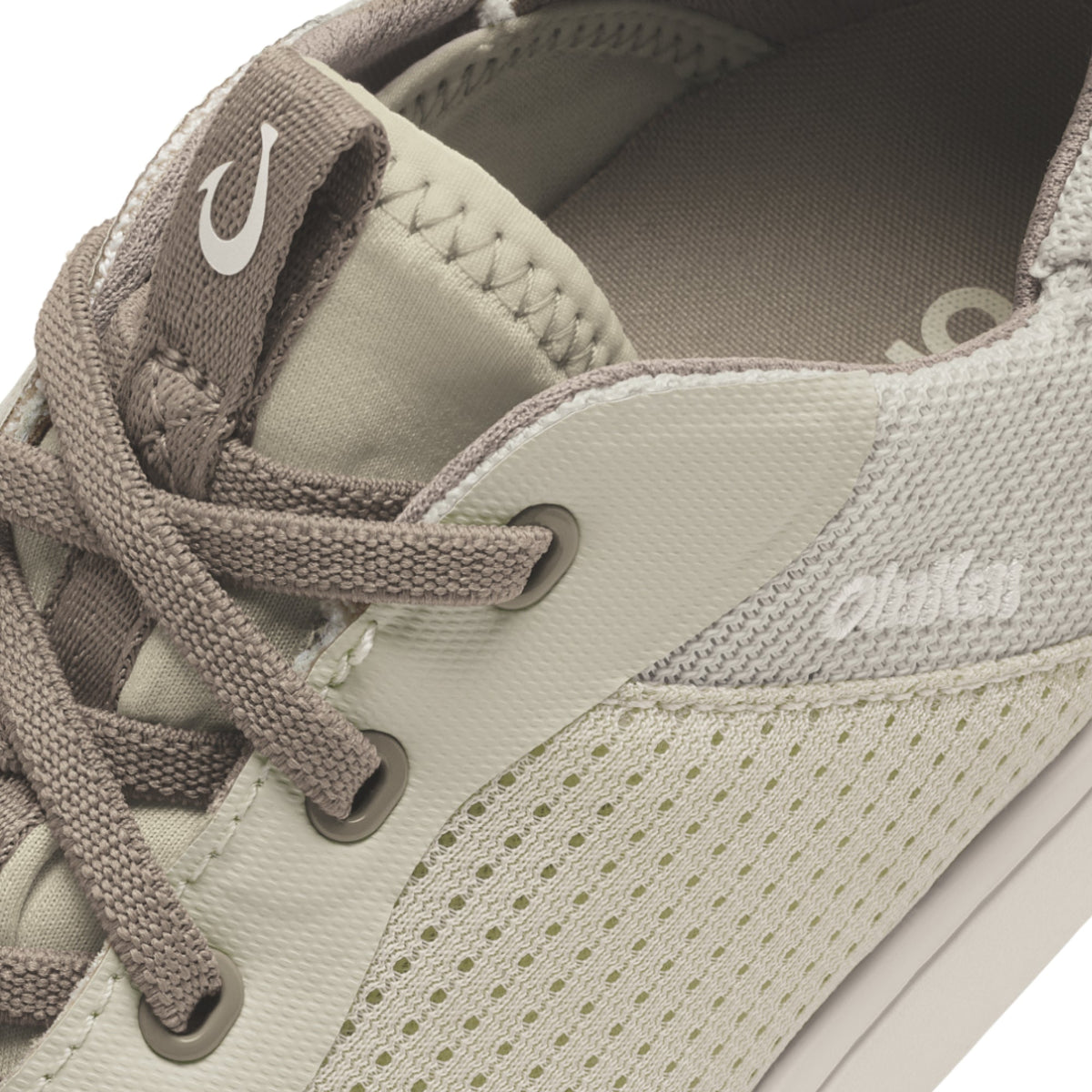 Beige and gray canvas sneaker with perforated side panels, gray laces, and white logo on tongue.