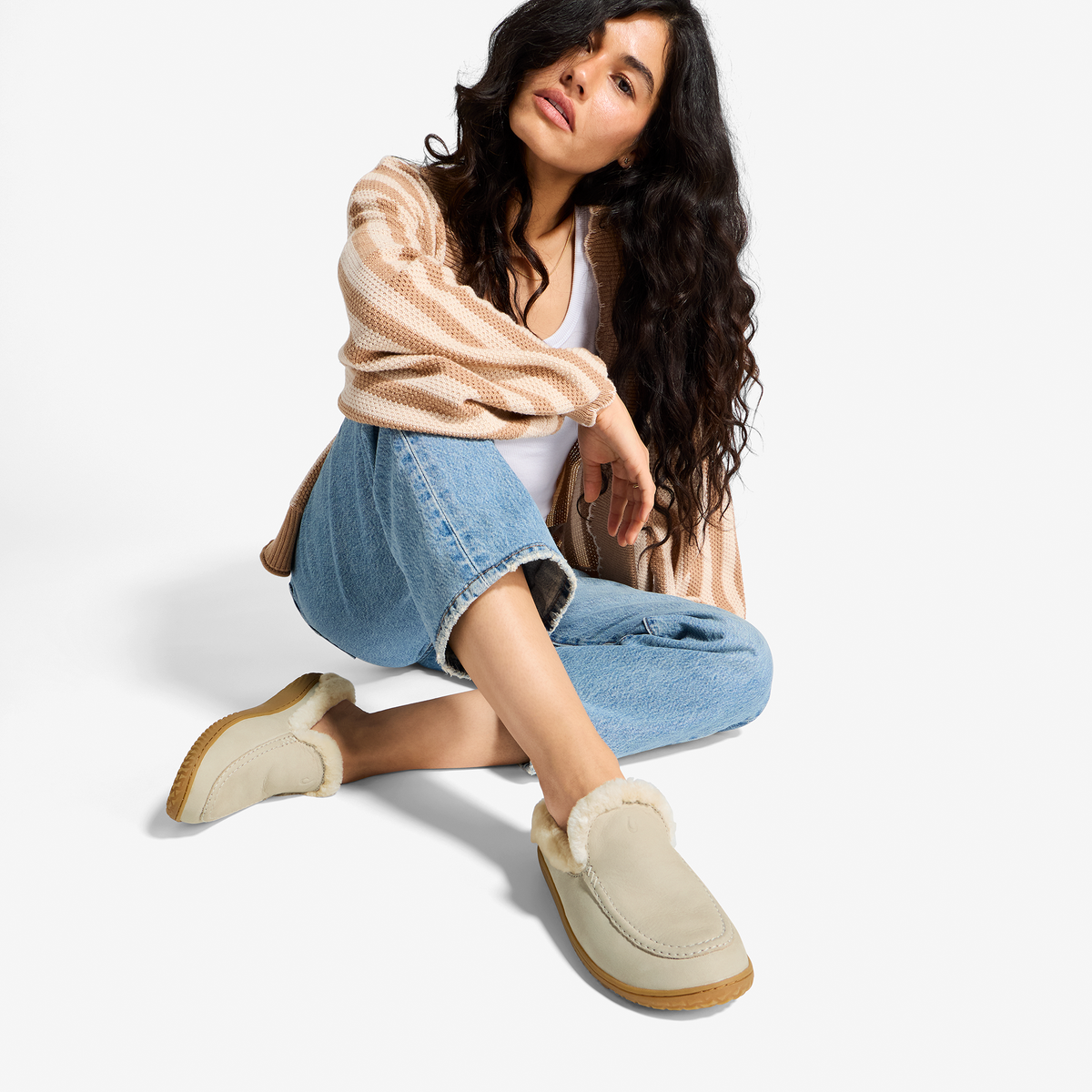 Ecru suede loafer slipper with crepe sole, shown worn with jeans and striped cardigan.
